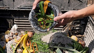 Des mains déversant des ordures dans le compost