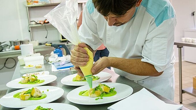 Réalisation d'un cahier de recettes Un restaurateur en train de réaliser son plat